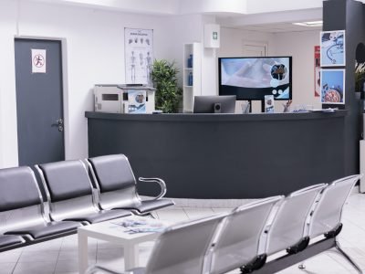 Clinical reception with waiting room in facility lobby, registration counter used for patients with medical appointments. Empty reception desk in health center for checkup visits.